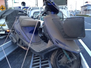 長期間放置されて埃が積もったスズキの原付スクーター。無料回収される様子が写っています。
