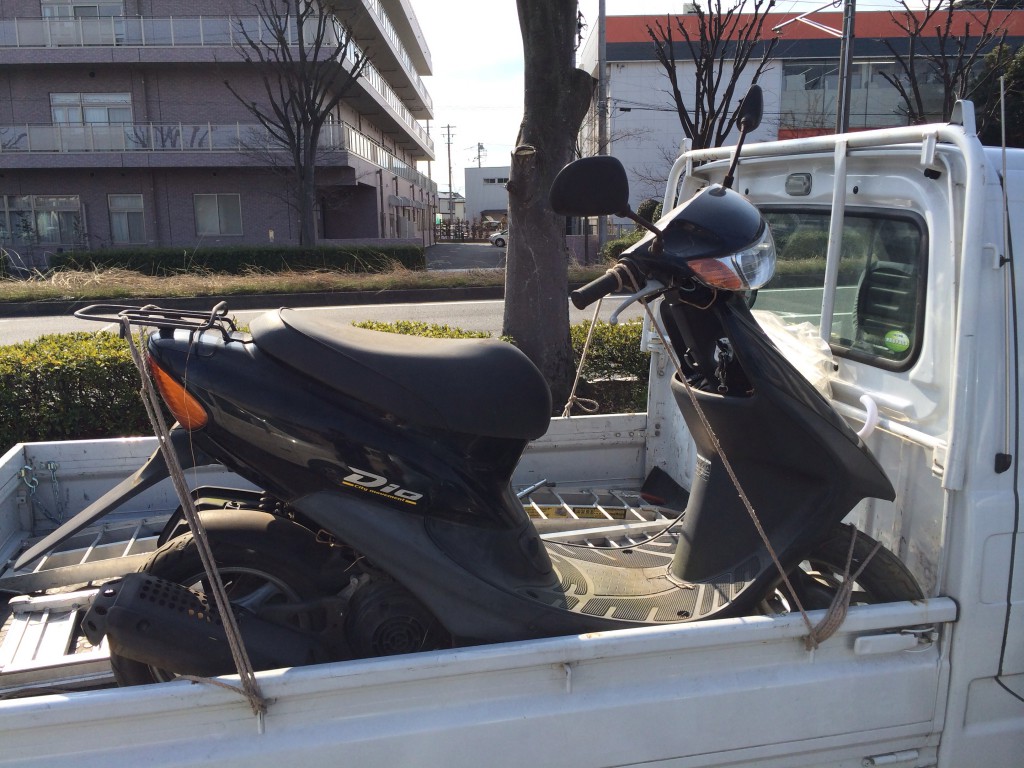 古い2サイクルのホンダ・ディオが軽トラックに積まれている。無料回収の現場。