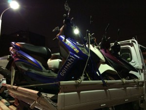 トラックの荷台に積まれた台湾仕様ヤマハ シグナスX FI。複数のスクーターと一緒に夜間に撮影されています。