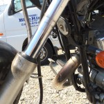 ヤマハ ビラーゴ250のエンジンとエキゾーストパイプ部分。フロントフォークからは経年に酔った劣化からかオイル漏れが確認できます。
