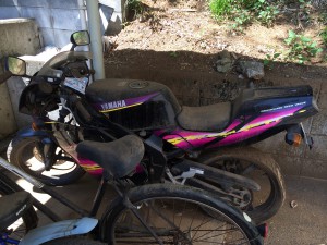 埃と泥に覆われたヤマハ TZR50Rの右側面写真。ピンクとイエローの純正グラフィックが特徴のフルカウルスポーツバイク。