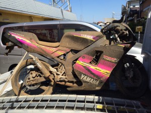 ヤマハ TZR50Rをトラック荷台に積載した状態の写真。埃まみれだが、フルカウルと車体は無事で再生可能な状態。