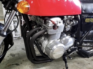 ホンダCB400FOURのエンジンとマフラー部分のクローズアップ写真。シルバーエンジンと黒いマフラーが美しく整備されている。