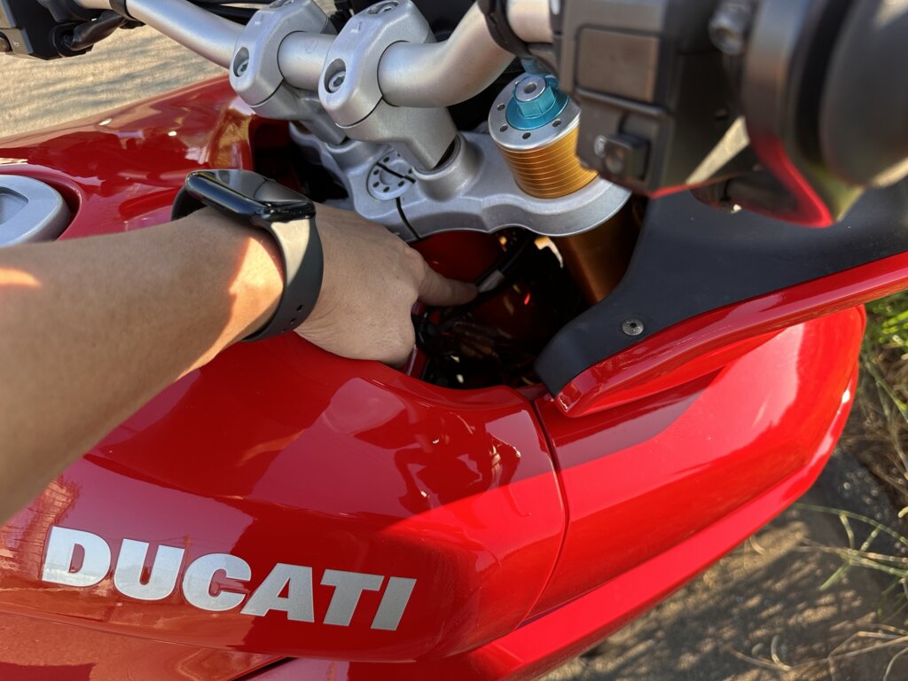 ドゥカティ ムルティストラーダ1100Sのフロントカウルを開け、車台番号の位置を指差している手元のクローズアップ画像