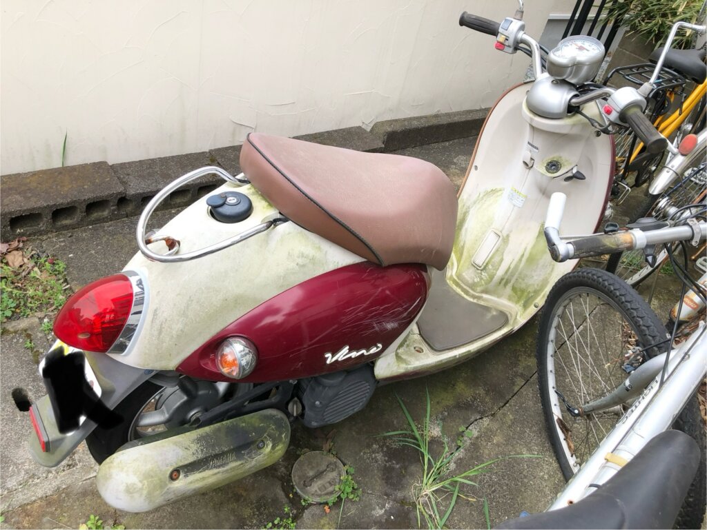 屋外に放置され、苔や汚れが目立つスクーター。バイク処分の重要性を伝える写真