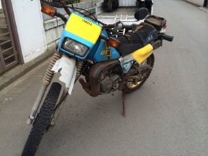 前方から撮影したヤマハ DT125。錆びたエンジン部分や劣化した外装が特徴的な不動車の状態を示す