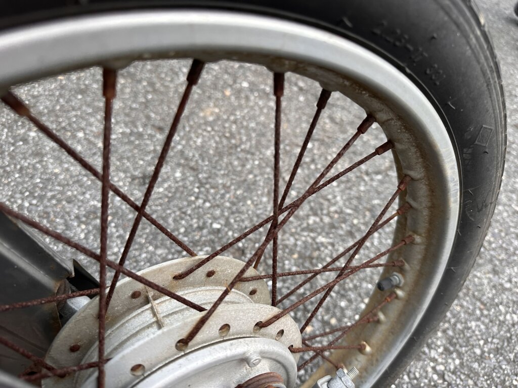 ホンダ・スーパーカブ50 カブラ仕様のホイールスポーク部分の写真。スポーク全体に錆が進行しており、リムにも汚れが見られる。