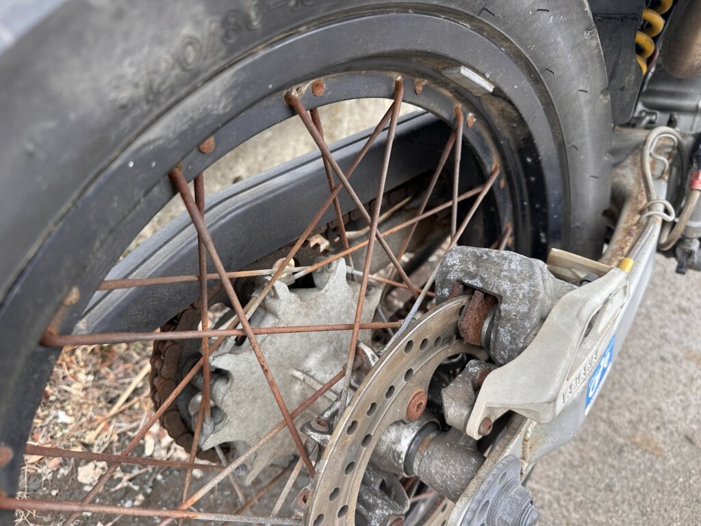 雨ざらし放置による錆が見られるヤマハ セロー225WEのリアホイールとブレーキ写真