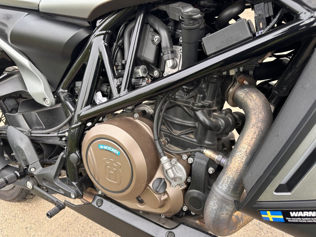 ハスクバーナ スバルトピレン701のエンジン部分のクローズアップ写真。力強い単気筒エンジンとトレリスフレーム構造が確認できる。
